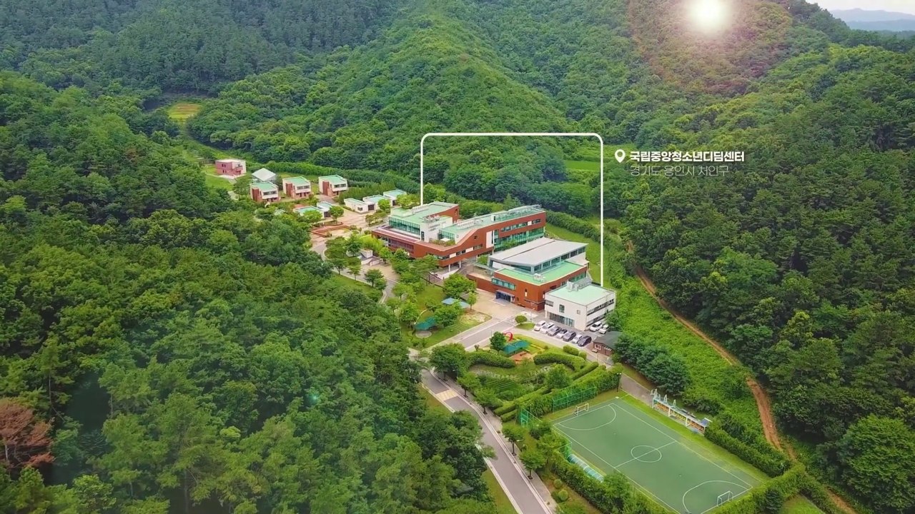 숲과 건물의 배치를 함께 보여주는 항공 영상 장면